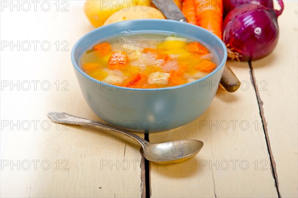 Traditional Italian minestrone soup on a rustic table with ingredients