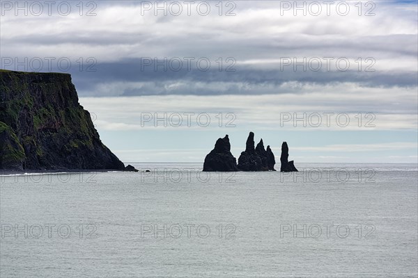 Cloudy sky over cliff with rock needles Reynisdrangar in summer