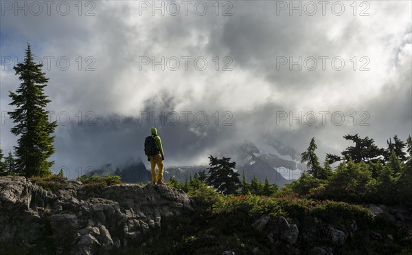 Hiker in front of cloudy Mt. Shuksan with snow and glacier