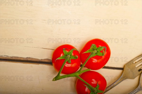 Ripe cherry tomatoes cluster over white rustic wood table