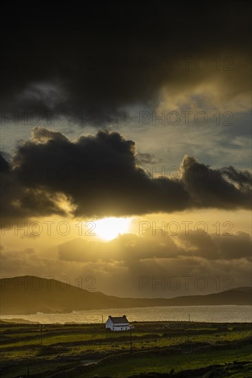 Small house on the sea coast in the backlight at golden hour