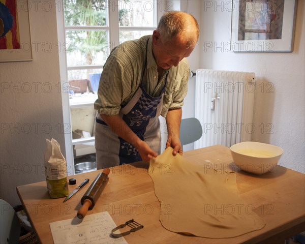 Man rolling out strudel dough at a table