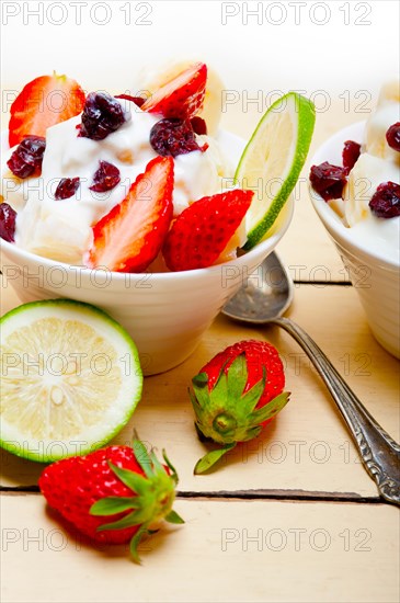 Fruit and yogurt salad healthy breakfast over white wood table