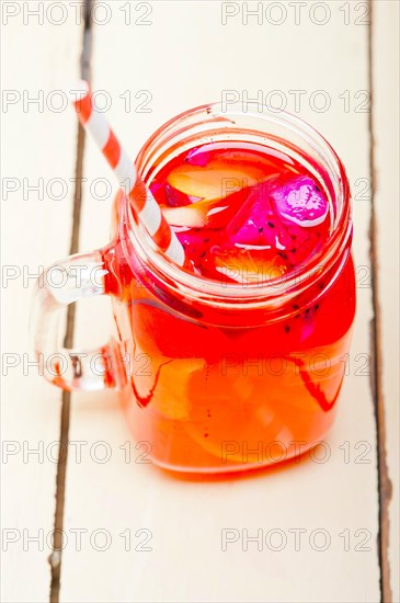 Fresh fruit punch refreshing summer drink over white rustic wood table