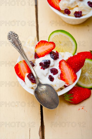 Fruit and yogurt salad healthy breakfast over white wood table