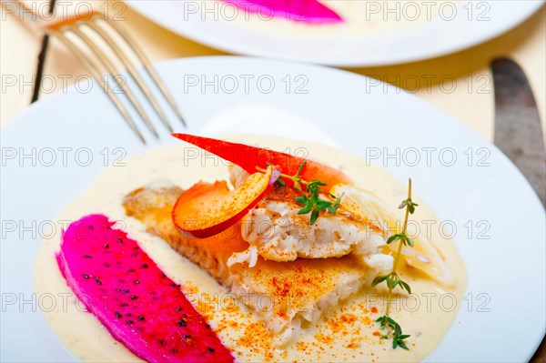 Sea bream orata fillet butter pan fried with fresh peach prune and dragonfruit slices thyme on top