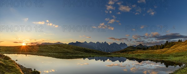 Salfainsee with reflection of the Kalkkoegel and mountaineers on mountain meadow at sunrise