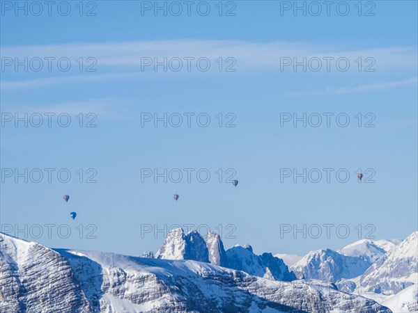 Hot air balloons flying over snow-covered Alpine peaks