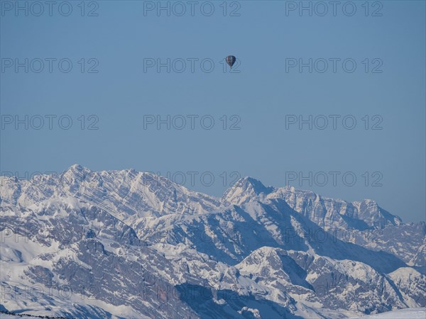 Hot air balloons flying over snow-covered Alpine peaks