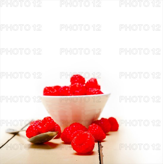 Bunch of fresh raspberry on a bowl and white wood rustic table