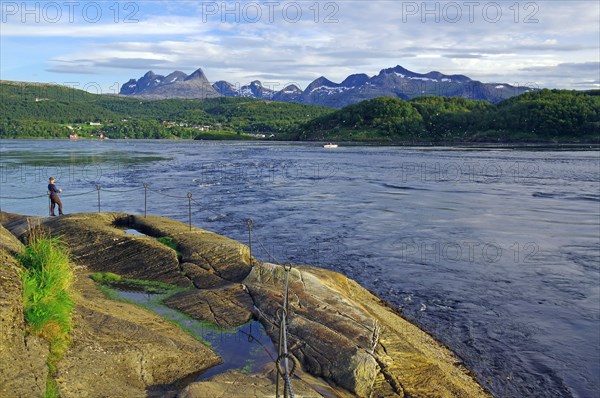 Angler standing on the bank of a fast flowing water