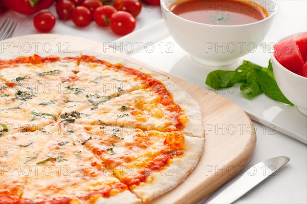 Italian original thin crust pizza Margherita with gazpacho soup and watermelon on side