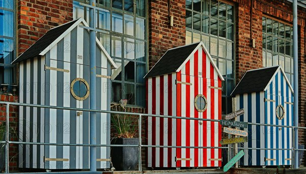 Three bathhouses in front of old industrial building