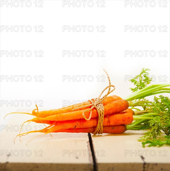 Fresh baby carrots bunch tied with rope on a rustic table