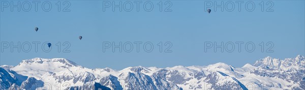 Hot air balloons flying over snow-covered Alpine peaks