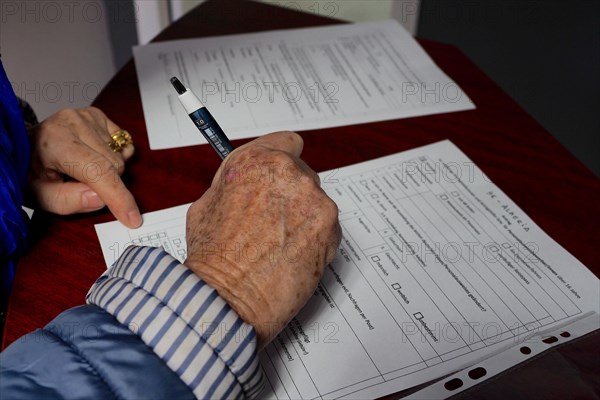 Old hands with a pen in the dog over a form