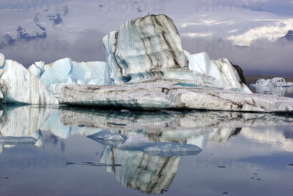 Iceberg with black stripes reflected in the water