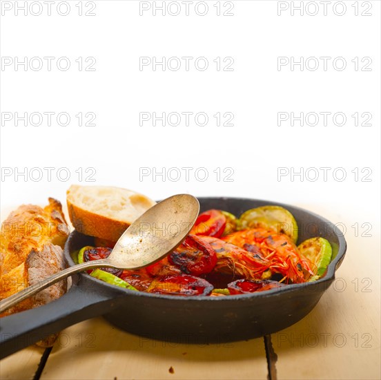 Roasted shrimps on cast iron skillet with zucchini and tomatoes