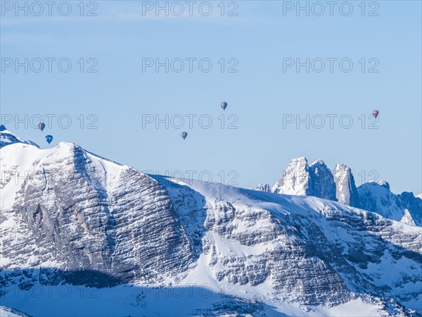 Hot air balloons flying over snow-covered Alpine peaks