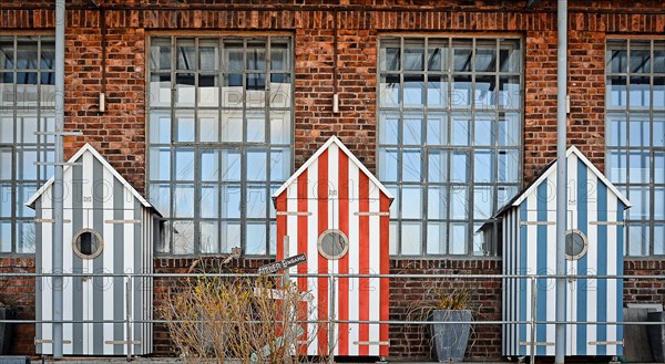 Three bathhouses in front of old industrial building