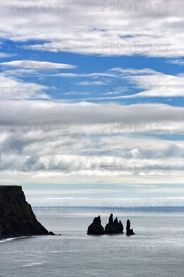 Cloudy sky over cliff with rock needles Reynisdrangar in summer