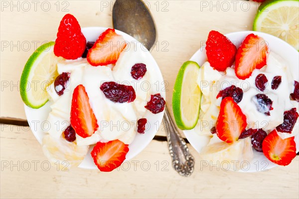 Fruit and yogurt salad healthy breakfast over white wood table