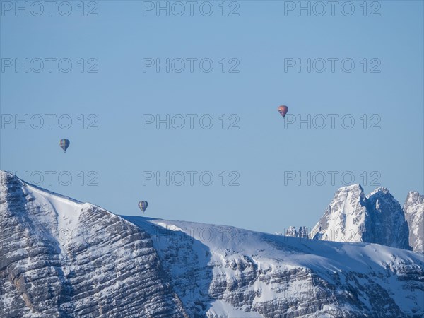 Hot air balloons flying over snow-covered Alpine peaks