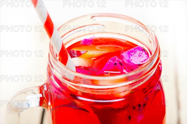 Fresh fruit punch refreshing summer drink over white rustic wood table