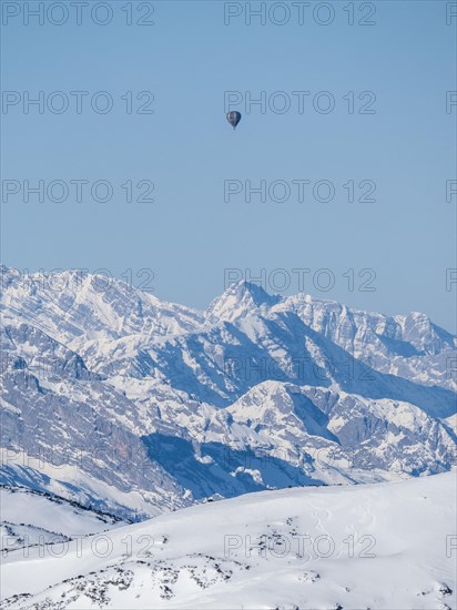 Hot air balloons flying over snow-covered Alpine peaks