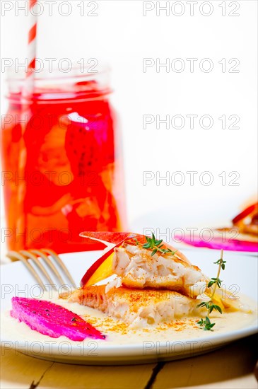 Sea bream orata fillet butter pan fried with fresh peach prune and dragonfruit slices thyme on top