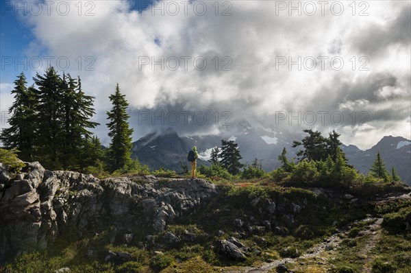 Hiker in front of cloudy Mt. Shuksan with snow and glacier