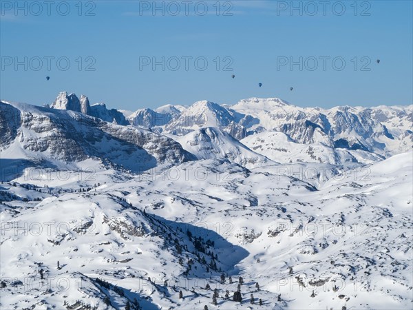 Hot air balloons flying over snow-covered Alpine peaks