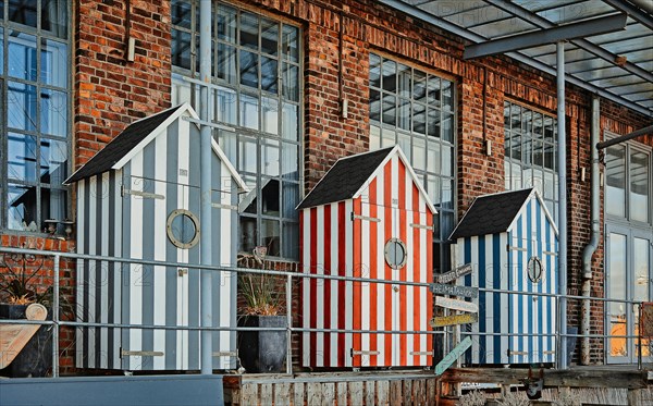 Three bathhouses in front of old industrial building