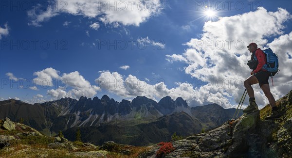 Mountaineer in the foreground in front of a backlit panorama of the Kalkkoegel peaks