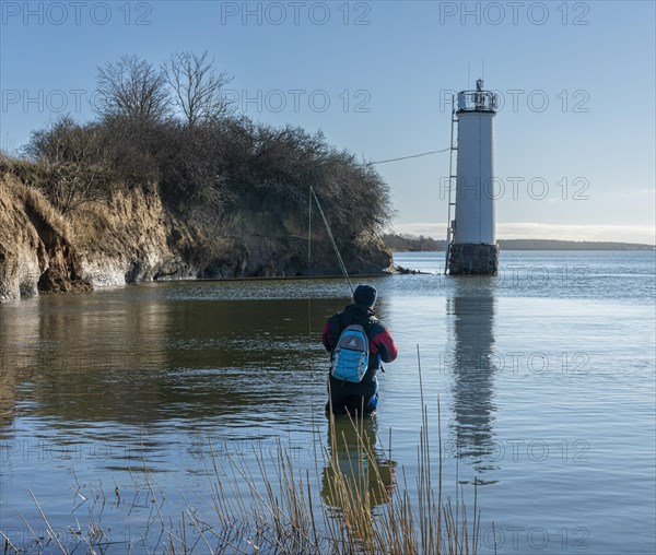 Angler standing in the water at the lighthouse of Maltzien on the island of Ruegen