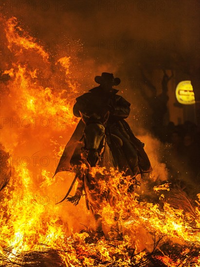 Arider with his horse jumping through a bonfire in an apocalyptic scene of Las Luminarias during the feast of St. Anthony held annually in the streets of the small mountain hamlet of San Bartolome de Pinares