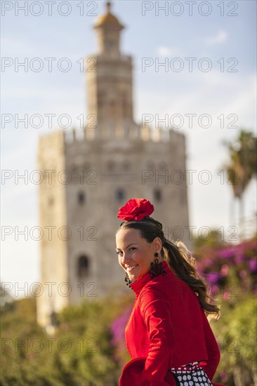 A beautiful young woman in front of the Torre del Oro on her way to the Feria de Abril in Seville