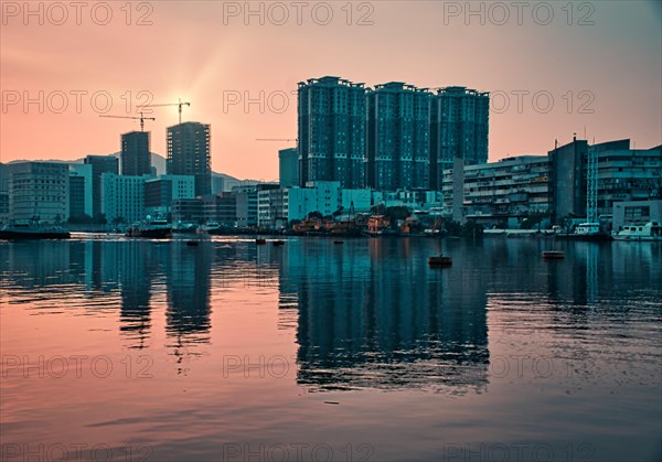 Tall buildings by the sea with reflections at sunset in Macau