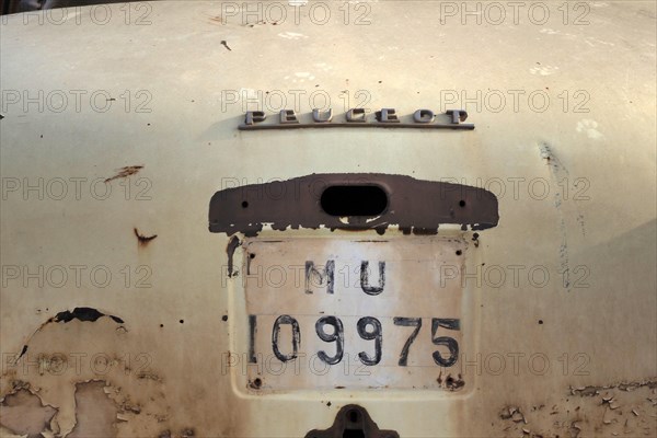 Rear of beige scrapped Peugeot with painted number plate