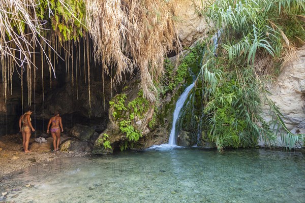 Two young women in one of the caves with a stream dating back to biblical times in the Negev desert in the Nature Reserve of Ein Gedi