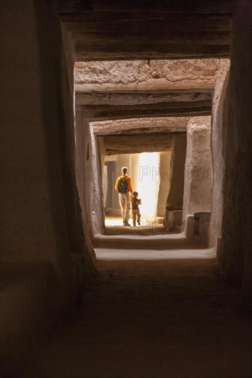 Aman and his daughter walking through tunnels of the unique mud city of the berbers in the oasis of Ghadames