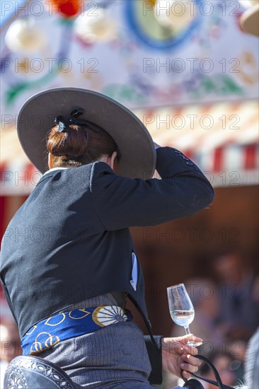 Detail of woman in traditional attire with sherry glass in hand during the Feria de Abril in Seville