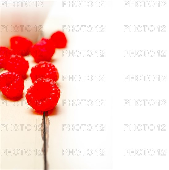 Bunch of fresh raspberry on a bowl and white wood rustic table