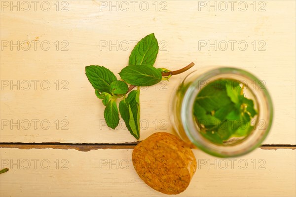 Fresh mint leaves on a glass jarover a rustic white wood table