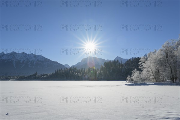 Frozen lake Barmsee with Karwendel mountainrange on morning with sun in winter