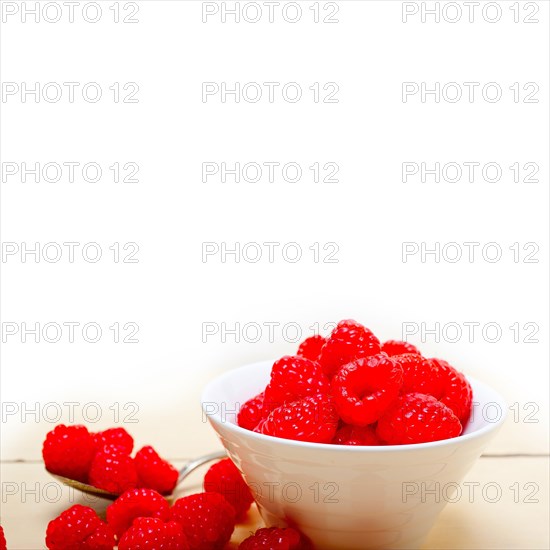 Bunch of fresh raspberry on a bowl and white wood rustic table