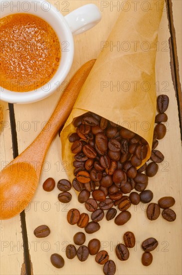 Espresso coffee and beans on a paper cone cornucopia over white background