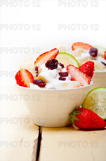 Fruit and yogurt salad healthy breakfast over white wood table