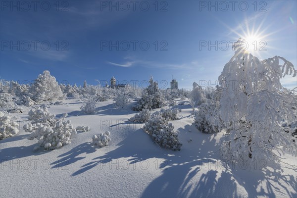 Snow covered winter landscape with sun Fichtelberghaus and weather station