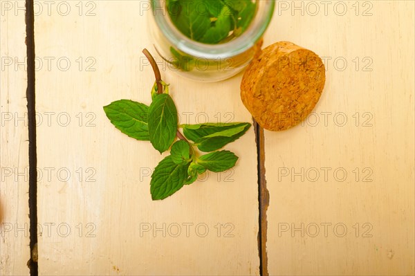 Fresh mint leaves on a glass jarover a rustic white wood table